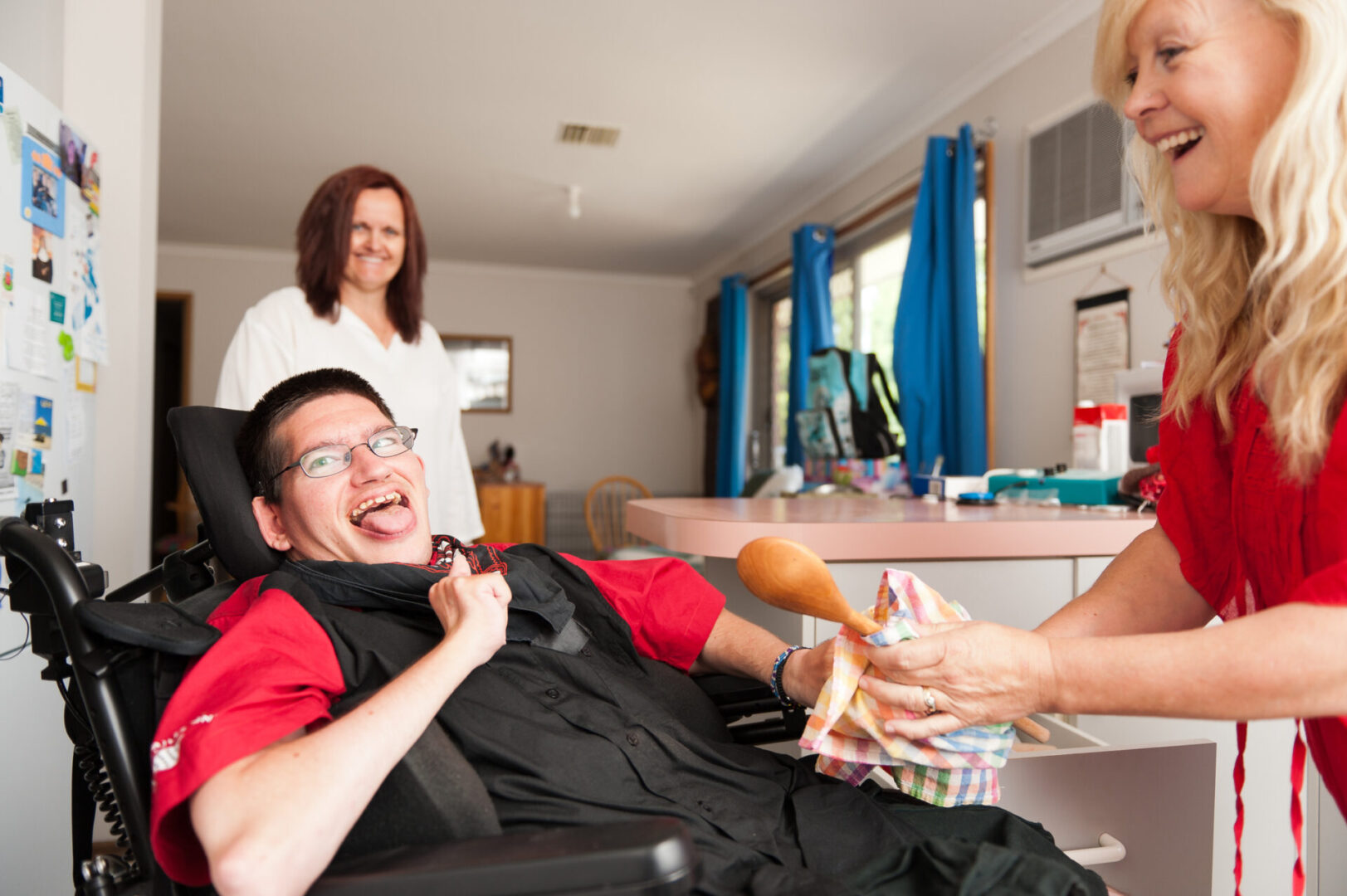 Young man being assisted to wipe dry a wooden spoon.