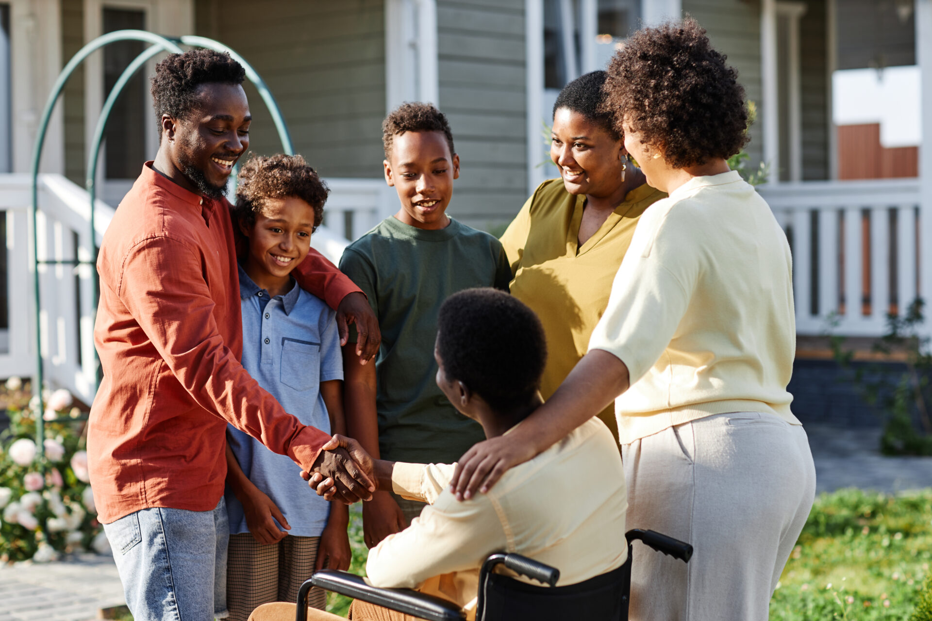 Portrait of big African American family with person in wheelchair chatting outdoors during gathering for party